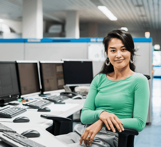 woman smiling in front of several computer screens