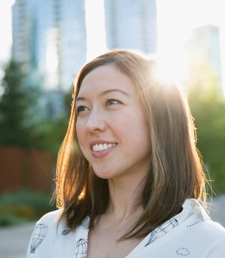 young woman smiling, the sun shines behind her